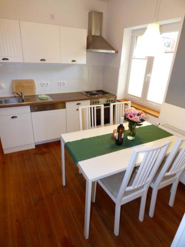 a kitchen with a white table and chairs and a table and a kitchen at Emely Ferienwohnungen in Röbel