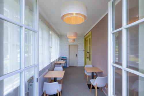 a row of tables and chairs in a room with windows at Aparthotel Panorama in Deštné v Orlických horách
