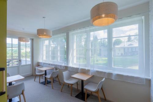 a waiting room with tables and chairs and windows at Aparthotel Panorama in Deštné v Orlických horách