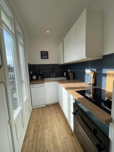 une cuisine avec des armoires blanches et un plancher en bois dans l'établissement Appartement 6 pers totalement rénové, à Merlimont
