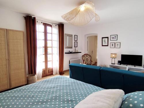 une chambre avec un lit bleu et une télévision dans l'établissement Appartement - Suze la Rousse, à Suze-la-Rousse