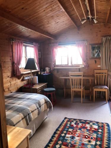 a bedroom with a bed and a table and chairs at The Old Log Cabin in Stow on the Wold