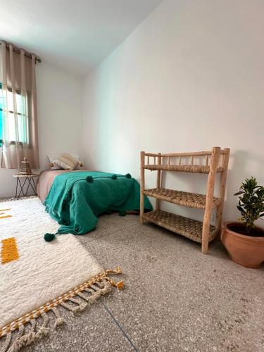 a bedroom with a bed with a green blanket on the floor at Dar Al-Andalus in Tamraght Ouzdar
