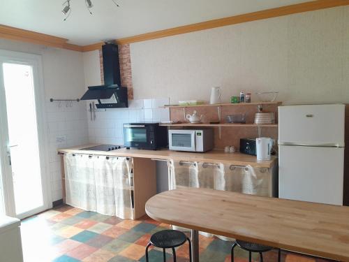 a kitchen with a table and a white refrigerator at Gîte meublé 10 personnes in Donges