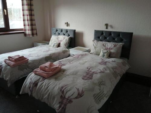 a bedroom with two beds with pink towels on them at Celicall in Ballater