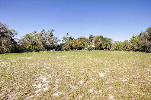 a large grass field with trees in the background at Peaceful Pomona Park Home 1 Mi to Lake Broward! in Satsuma