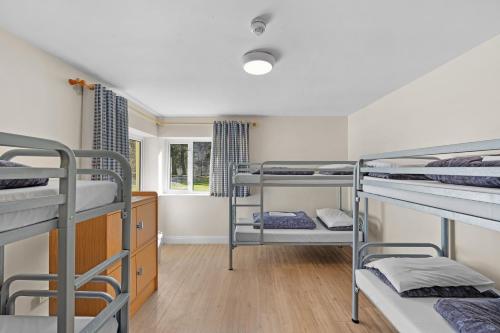 a room with three bunk beds and a window at Glendalough International Youth Hostel in Laragh