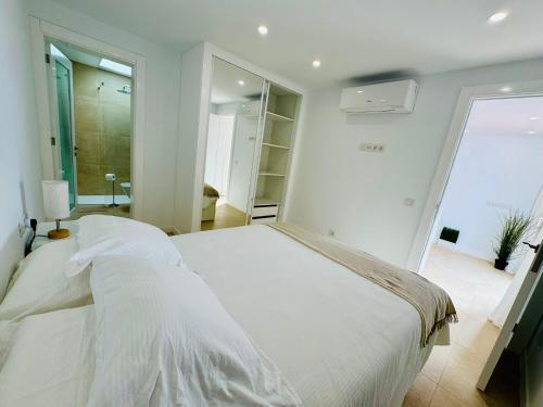 a white bedroom with a large bed and a bathroom at Bungalow Timple 2 in Puerto del Carmen