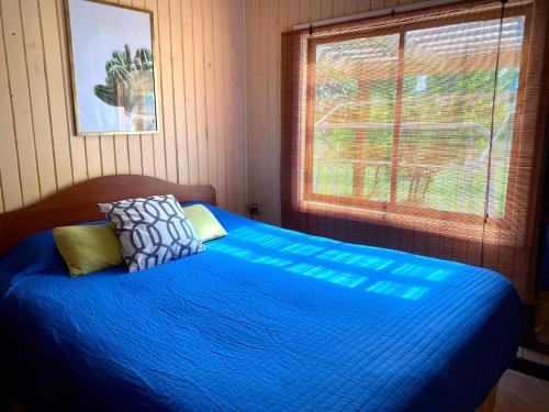 a bedroom with a bed with blue sheets and a window at Casa comoda in Salto del Laja