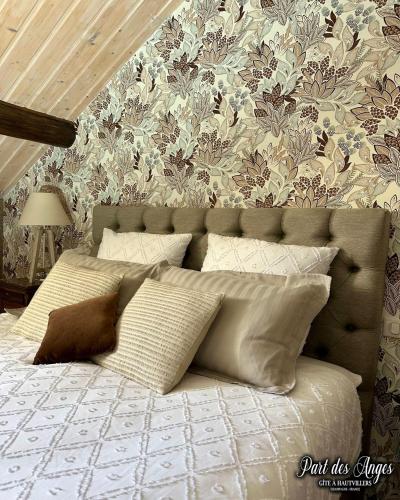 a bed with pillows in a bedroom with floral wallpaper at Part des Anges - Gîte Hautvillers in Hautvillers