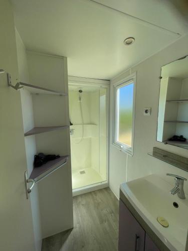 a white bathroom with a shower and a sink at Low Budget - Luxe 4 persoons chalet met TV aan het Lauwersmeer in Lauwersoog