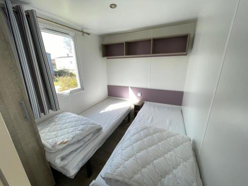 a small room with two beds and a window at Low Budget - Luxe 4 persoons chalet met TV aan het Lauwersmeer in Lauwersoog