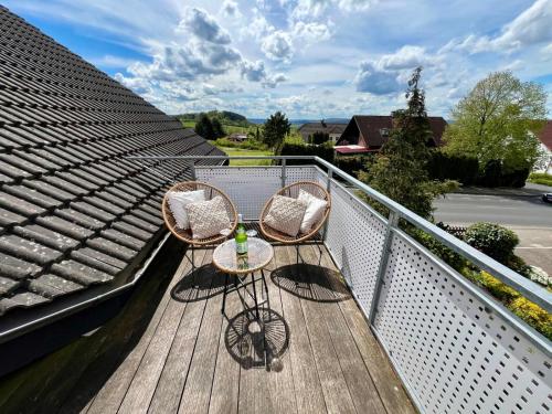 a balcony with two chairs and a table on it at flair Apartment Stadtoase Fulda I Whirlpool I Balkon I 2x Parken I Kaffee I Highspeed WLAN I Disney plus in Fulda
