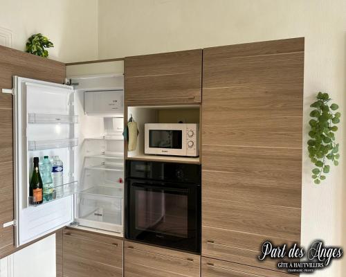 a kitchen with a microwave and an open refrigerator at Part des Anges - Gîte Hautvillers in Hautvillers