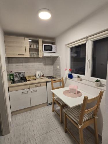 a kitchen with a table and chairs and a kitchen with a sink at A&M studio apartman in Otočac