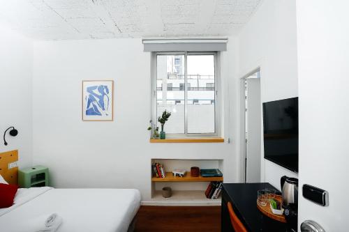 a white bedroom with a bed and a window at Domus Metro Hotel in Tel Aviv