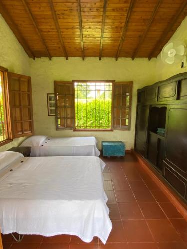 a room with four beds in it with windows at Finca chalet El Robledal in Pueblo Tapao