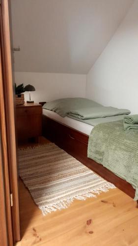 a bedroom with a bed and a table and a rug at Lesna Kryjowka Roztocze in Rybnica