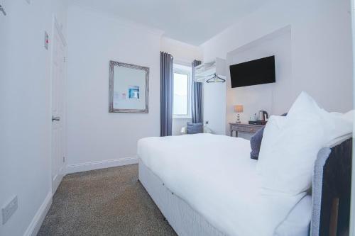a white bedroom with a white bed and a television at OYO Pier Hotel in Clacton-on-Sea