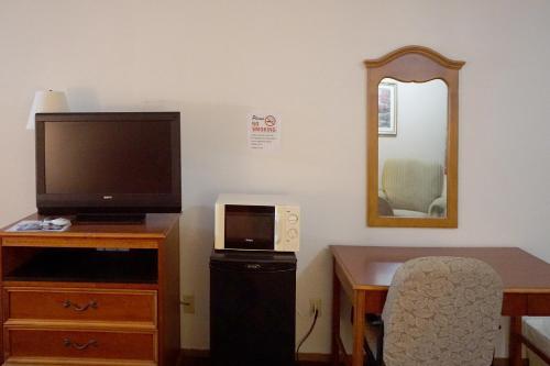 a room with a desk with a television and a table with a chair at OYO Hotel Altus N Main St in Altus