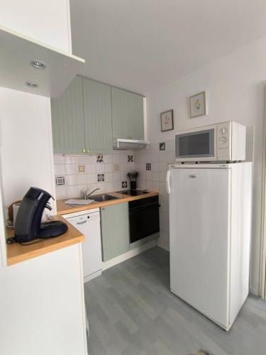 La cuisine est équipée d'un réfrigérateur blanc et d'un four micro-ondes. dans l'établissement La Lanterne, à Villers-sur-Mer