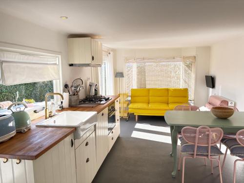 a kitchen with a yellow couch in a living room at George's Lodges Renesse in Renesse