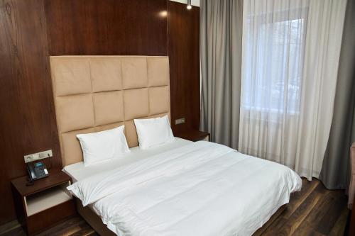 a bedroom with a large white bed with a window at Vogue hotel in Almaty