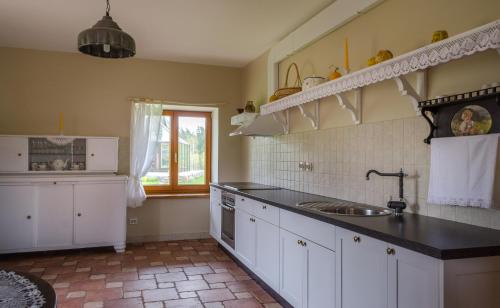 a kitchen with white cabinets and a sink and a window at Pūjalgi in Ēdole