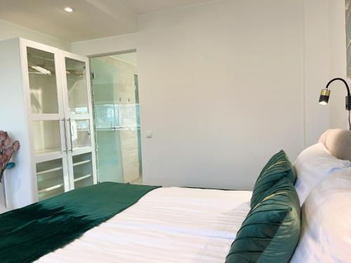 a bedroom with a white bed with green pillows on it at Magnolia House with Indoor Swimming Pool and Sauna in Tallinn