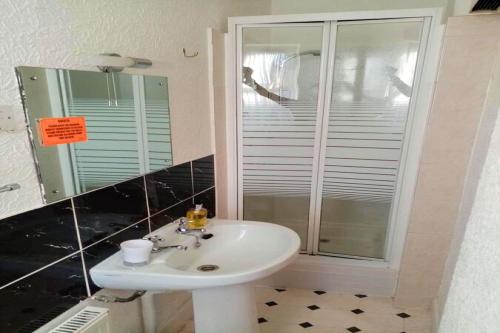 a bathroom with a sink and a shower with a mirror at Fjaerland Hotel in Great Yarmouth