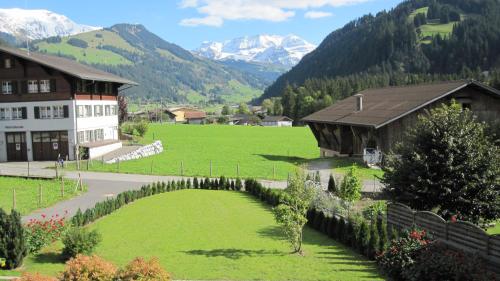 a house in a green field with mountains in the background at Gästehaus Alpenblick Wildstrubel in Sankt Stephan