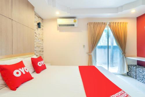 a bedroom with a bed with red pillows and a window at OYO 926 Sydney Resort in Ban Don Pho
