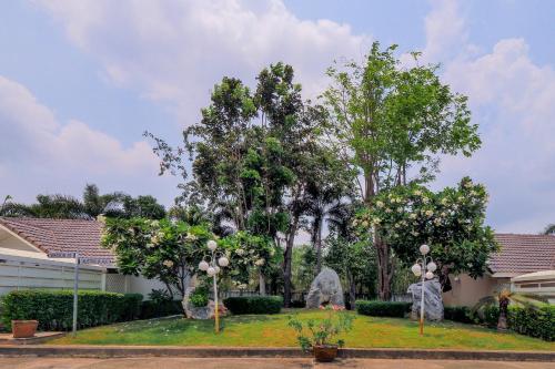 a garden with trees and statues in front of a building at OYO 926 Sydney Resort in Ban Don Pho