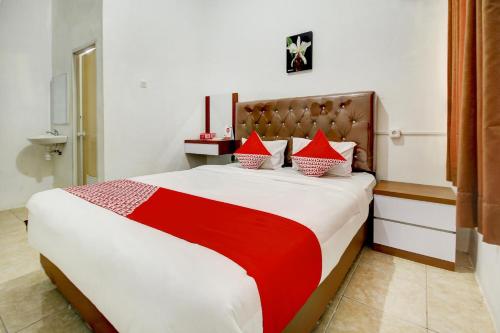 a bedroom with a large bed with red and white pillows at OYO Life 3415 Penginapan Wimane in Sukarami