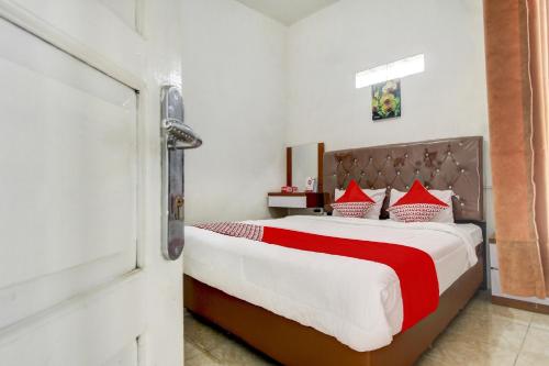 a bedroom with a large bed with red and white pillows at OYO Life 3415 Penginapan Wimane in Sukarami