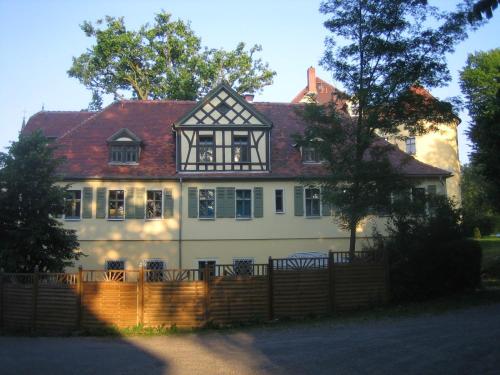 a white house with a fence in front of it at Schloßpension Hummelshain in Hummelshain