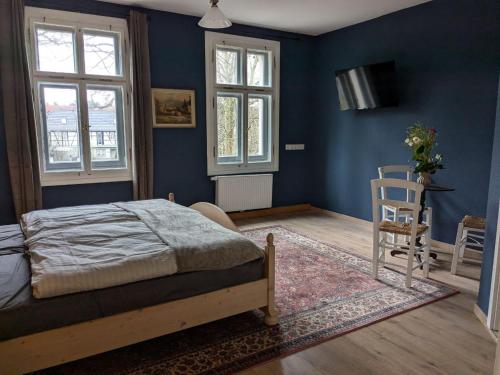 a bedroom with blue walls and a bed and a chair at Schloßpension Hummelshain in Hummelshain