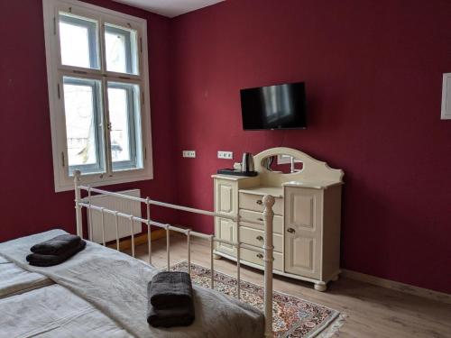 a bedroom with a bed and a tv on a red wall at Schloßpension Hummelshain in Hummelshain