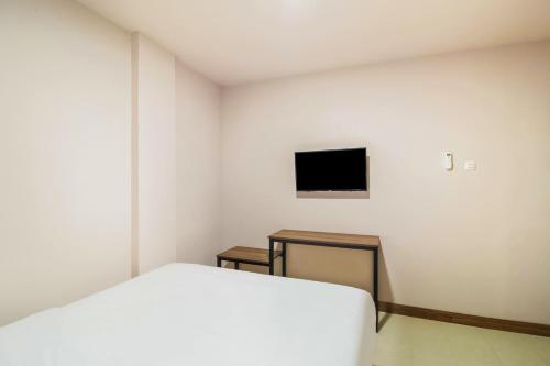 a bedroom with a bed and a tv on the wall at Collection O Kebon Jeruk Near Paskal 23 Formerly Sentral Paskal in Bandung