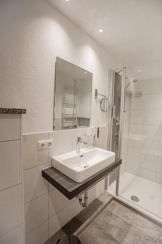 a white bathroom with a sink and a shower at Der Lärchenhof Ferienwohnungen in Schönau am Königssee