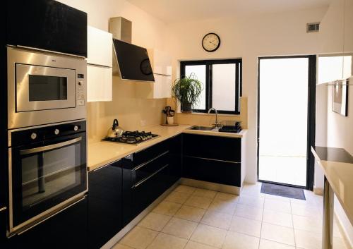 a kitchen with black cabinets and a stove top oven at Spacious 3 Bed Apartment in Vibrant St Julians in Tal-Għoqod