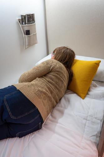 a woman laying on a bed with her head on a pillow at APTC ETXEa in Vitoria-Gasteiz
