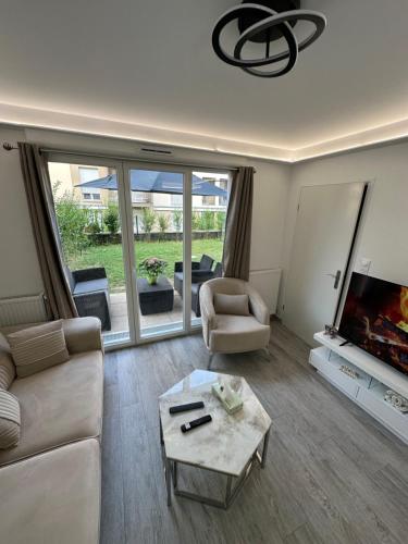 un salon avec un canapé, une télévision et une table dans l'établissement Appartement avec jardin cosy près de Paris, à Villeneuve-le-Roi