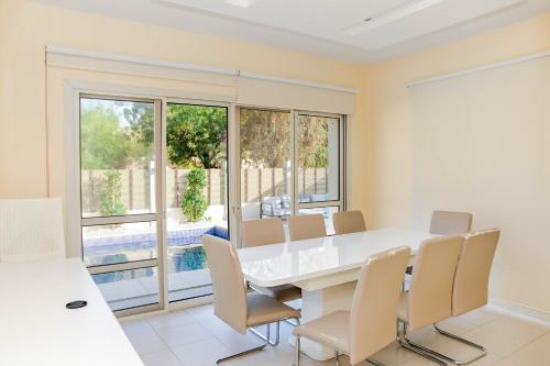 a dining room with a white table and chairs at Luxurious 6-BHK Villa with Private Pool in Malibu in Ras al Khaimah