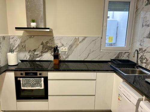 a kitchen with white cabinets and a black counter top at Apartamentos vinarós a 300m de la playa in Vinarós