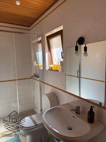 a bathroom with a sink and a toilet and a mirror at Casa do Rio, Sever do Vouga in Paradela