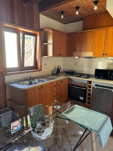 a kitchen with wooden cabinets and a glass table at Casa do Rio, Sever do Vouga in Paradela