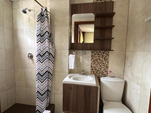 a bathroom with a sink and a toilet and a mirror at Hotel Casa Santa Lucía in Baños