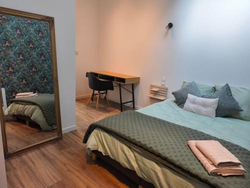 une chambre avec un lit, un miroir et un bureau dans l'établissement L'échappée verte, à Amiens