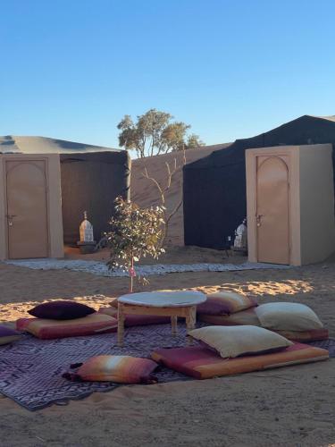 a group of pillows on the ground with a table at Moroccan Desert Camp in Merzouga